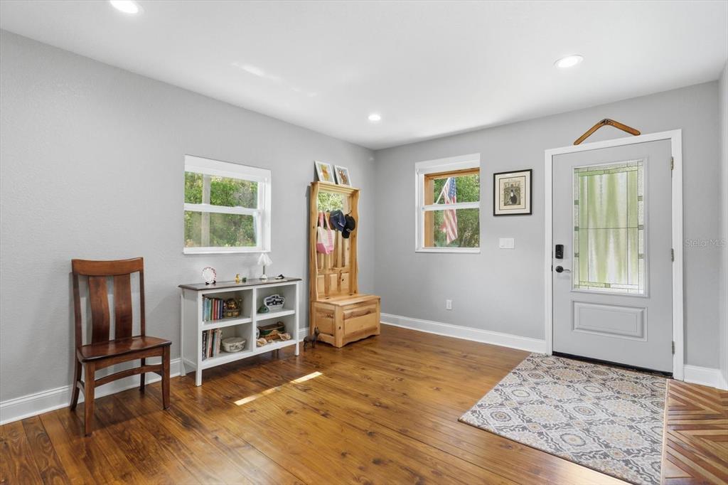 An entryway features light gray walls, hardwood floors, a white console table, and a front door — 4099 W RIDGE LANE, DUNNELLON, FL