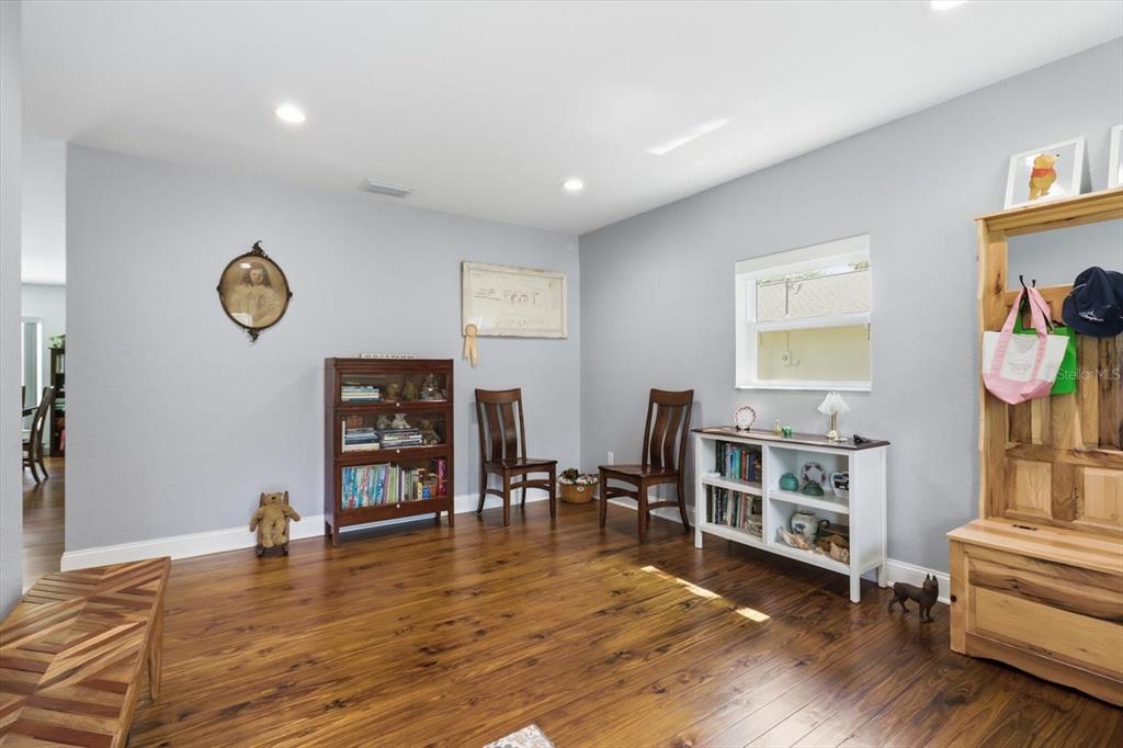 A room with wood flooring, light gray walls, two wooden chairs, and two bookcases — 4099 W RIDGE LANE, DUNNELLON, FL