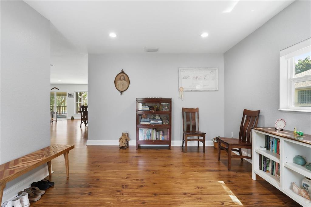A room with light gray walls, wood flooring, a wooden bookcase, and two wooden chairs — 4099 W RIDGE LANE, DUNNELLON, FL