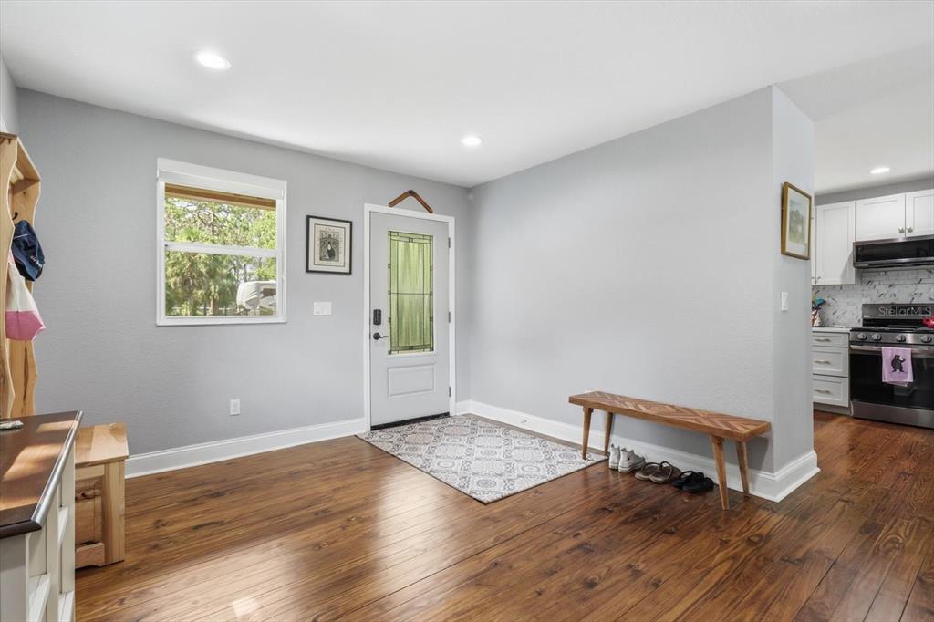 An entryway with hardwood floors, a wooden bench, a patterned rug, and a front door — 4099 W RIDGE LANE, DUNNELLON, FL