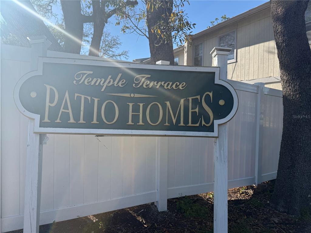 A sign for Temple Terrace Patio Homes stands in front of a white privacy fence — 5118 TENNIS COURT CIRCLE, TAMPA, FL