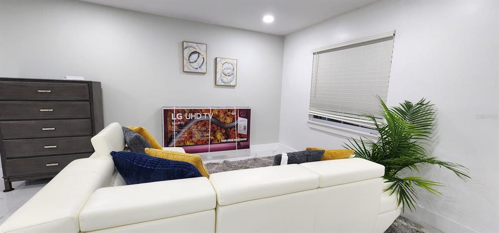 A living room features a white sectional sofa, a dresser, and a boxed television — 5118 TENNIS COURT CIRCLE, TAMPA, FL