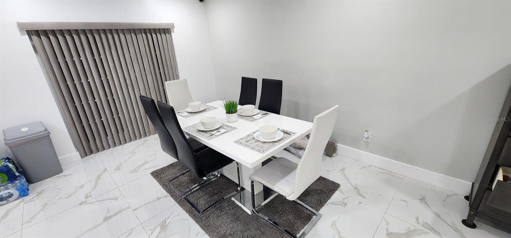A dining room features a white table, mixed black and white chairs, and tile flooring — 5118 TENNIS COURT CIRCLE, TAMPA, FL