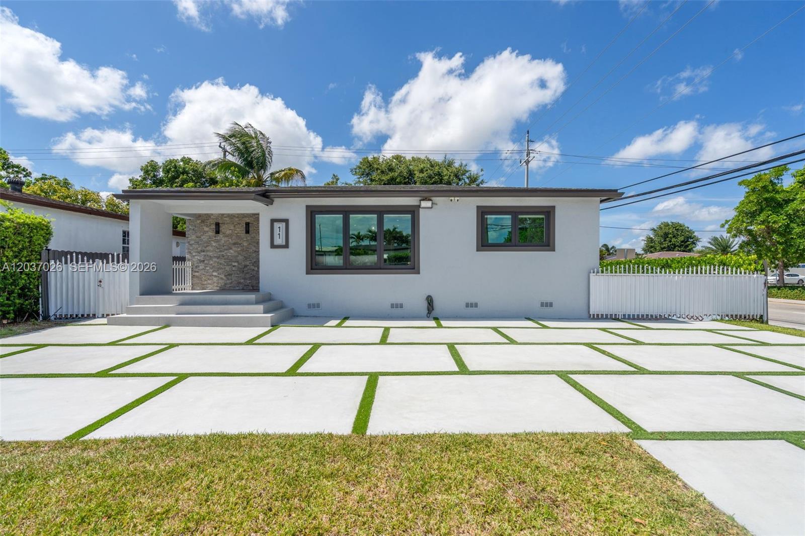 A single-story house features a light gray exterior, stone-accented entryway, and a paved driveway — 11 W 59th St, Hialeah FL 33012, HIALEAH, FL
