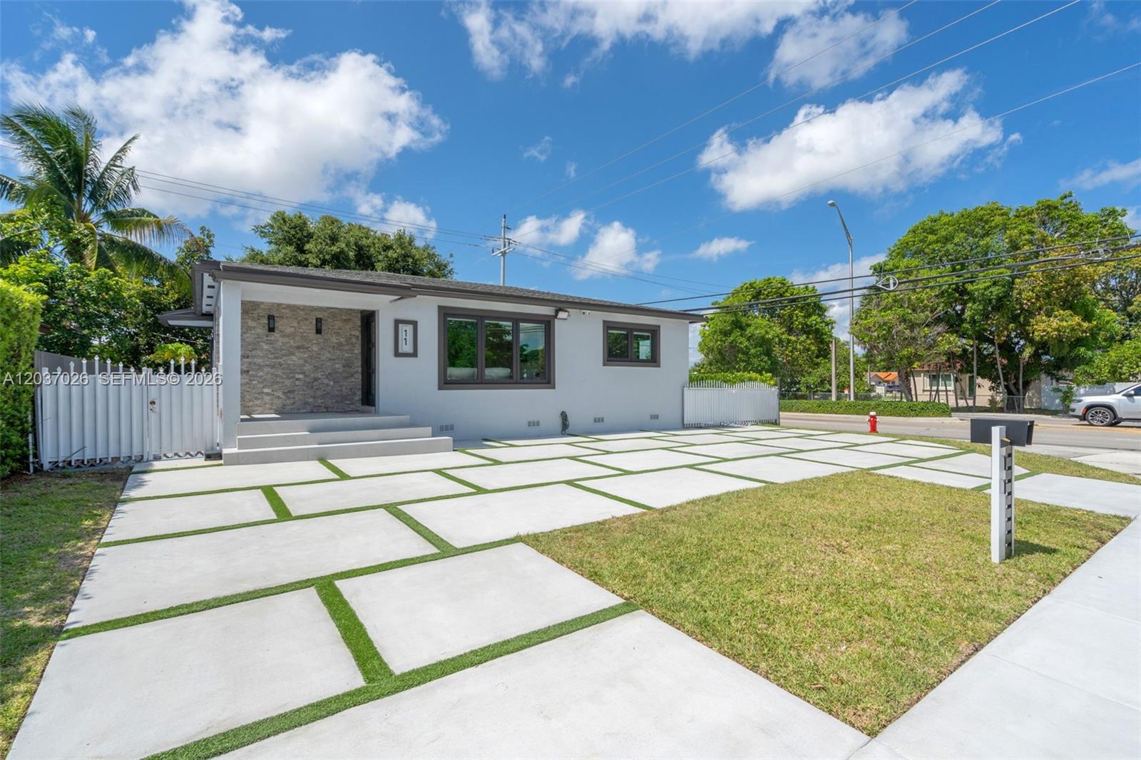 A single-story house features a stone-accented entryway, a large window, and a grid-patterned concrete driveway — 11 W 59th St, Hialeah FL 33012, HIALEAH, FL