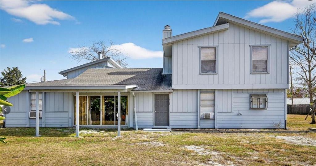 A two-story house with light gray vertical siding, a covered patio, and a gray door — 2519 FERN PALM DRIVE, EDGEWATER, FL