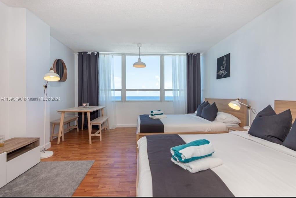 A bedroom with two beds, a dining area, and a large window overlooking the ocean — 5445 Collins Ave # 1735, Miami Beach FL 33140, MIAMI BEACH, FL