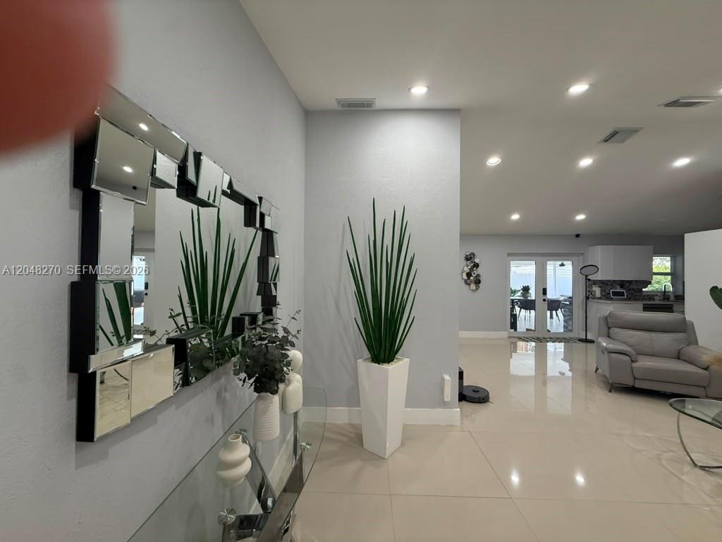 A modern entryway features a large segmented mirror, a tall potted plant, and tiled floors — 14305 SW 182nd Ter # 0, Miami FL 33177, MIAMI, FL