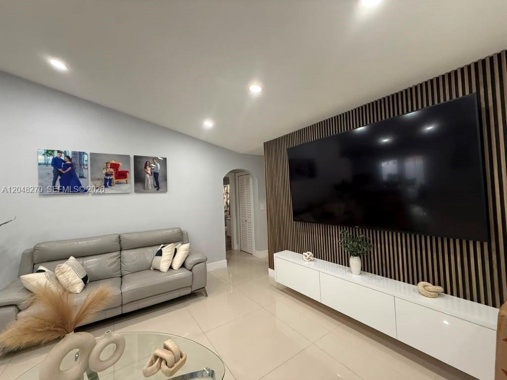 A living room features a large wall-mounted television, wood slat paneling, and a gray sofa — 14305 SW 182nd Ter # 0, Miami FL 33177, MIAMI, FL