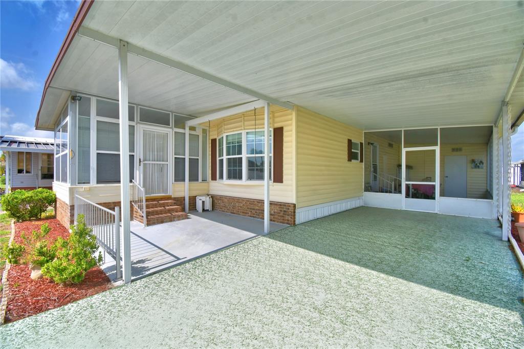 A mobile home exterior featuring a covered carport, a concrete patio, and a screened-in porch — 4807 PLUMWOOD STREET, WINTER HAVEN, FL