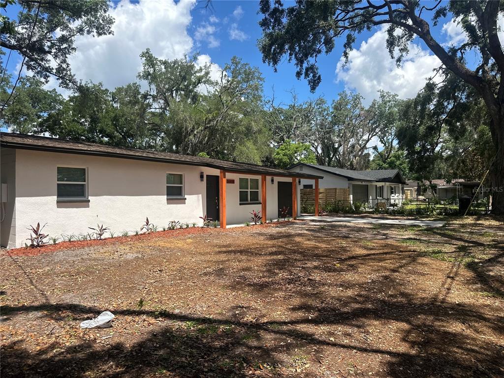 A single-story house with a white stucco exterior and a wooden porch structure — 14808 N 30TH STREET, LUTZ, FL