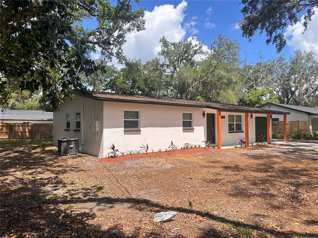 A single-story house with a light-colored stucco exterior, dark trim, and a wooden porch — 14808 N 30TH STREET, LUTZ, FL
