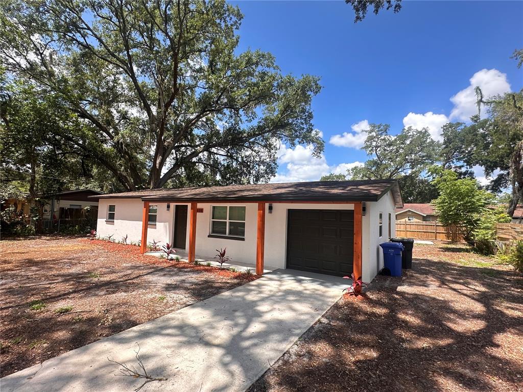 A single-story house with a white exterior, wooden porch posts, and an attached garage — 14808 N 30TH STREET, LUTZ, FL