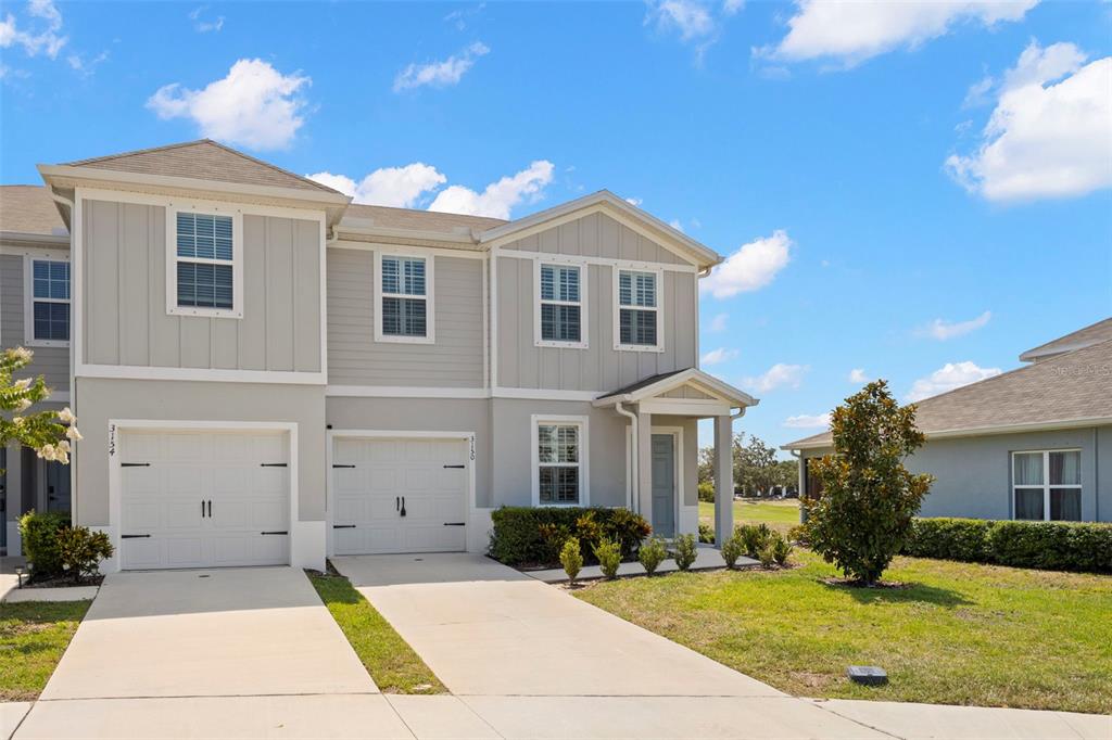 A two-story duplex with beige siding, two garage doors, and a small front porch — 3150 VICTORIA INLET DRIVE, HOLIDAY, FL