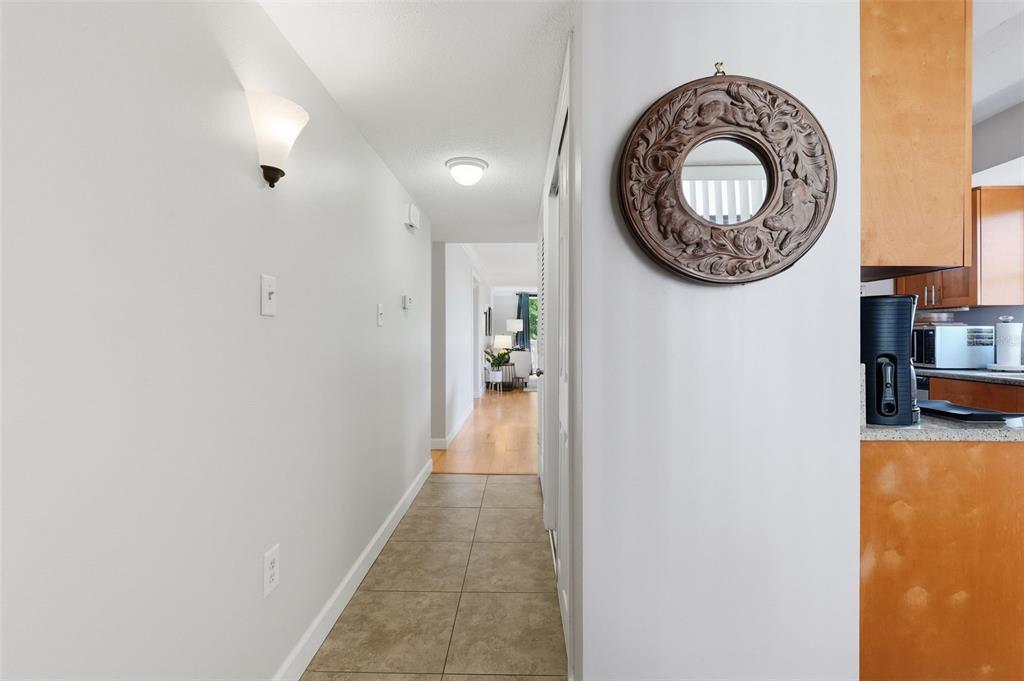 A tiled hallway leads to a living area with wood flooring and a decorative mirror — 2612 PEARCE DRIVE UNIT 211, CLEARWATER, FL