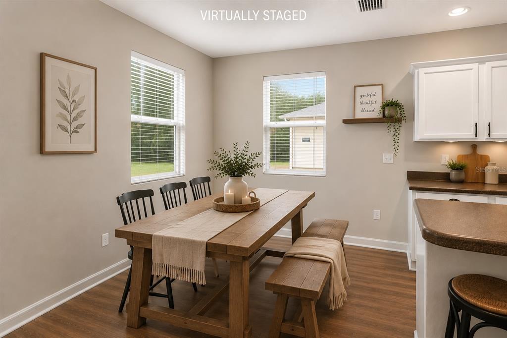 This virtually staged dining area features a wooden table, bench seating, and white kitchen cabinets — 2637 WALDEN WOODS DRIVE, PLANT CITY, FL