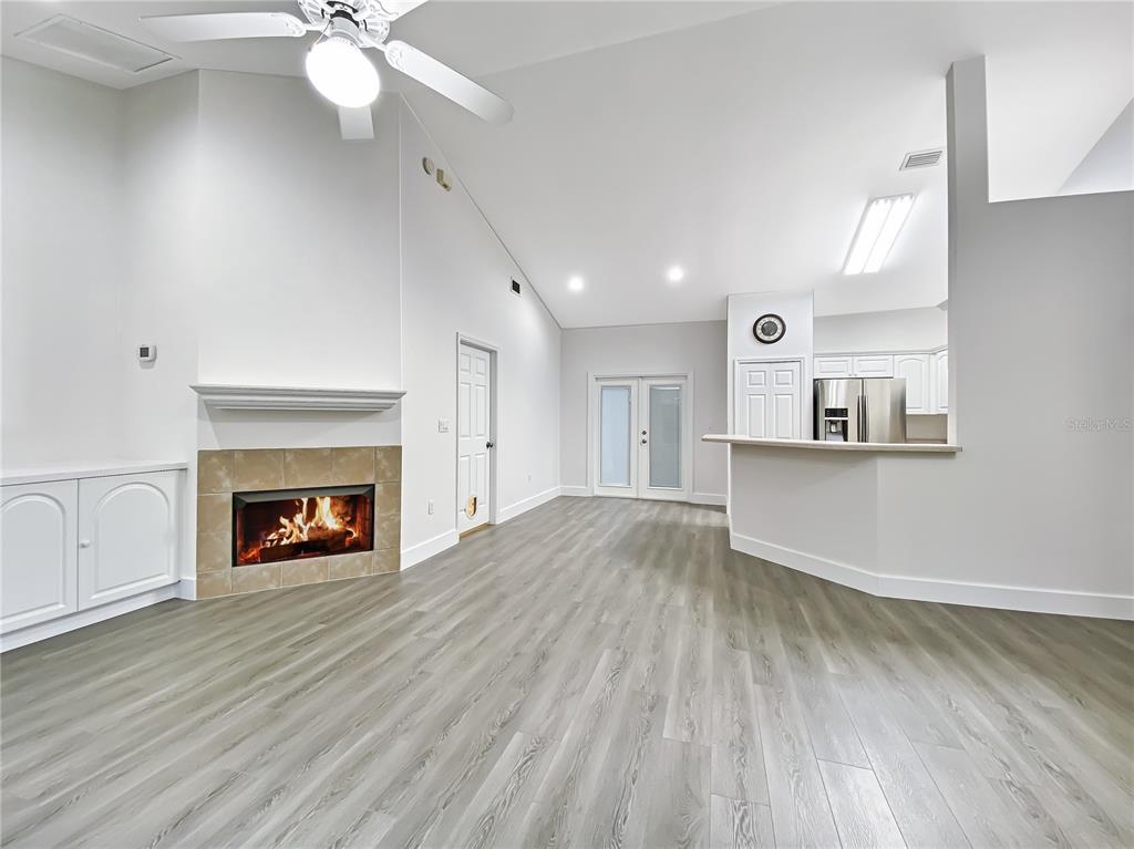 A living room with a fireplace, vaulted ceiling, and light wood-look flooring — 10301 SW 52ND AVENUE, GAINESVILLE, FL
