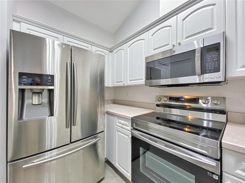 A kitchen features white cabinetry, stainless steel appliances, and light-colored countertops — 10301 SW 52ND AVENUE, GAINESVILLE, FL