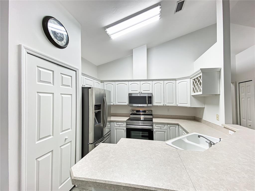 A kitchen features white cabinets, stainless steel appliances, and a light-colored countertop — 10301 SW 52ND AVENUE, GAINESVILLE, FL