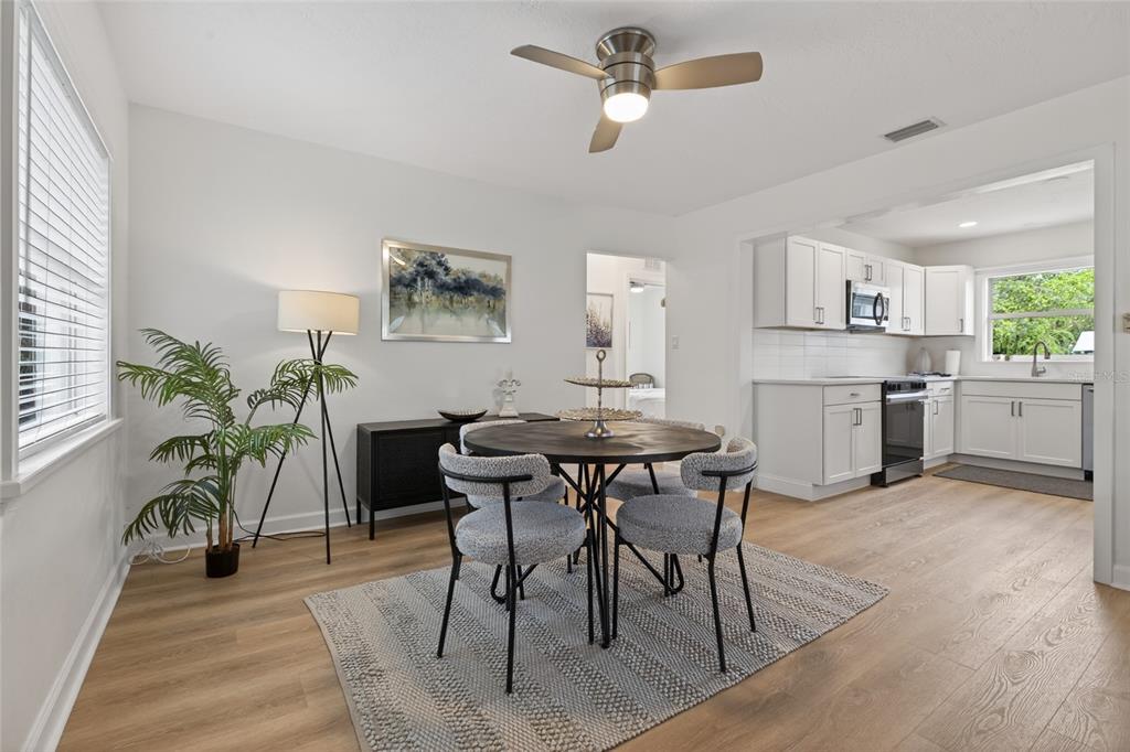 A dining area with a round table and chairs sits adjacent to a white kitchen — 5617 19TH AVENUE S, ST PETERSBURG, FL