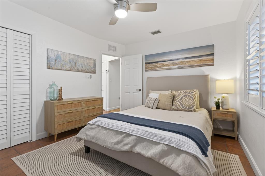 A bedroom features a bed with a beige headboard, a wooden dresser, and tile flooring — 5617 19TH AVENUE S, ST PETERSBURG, FL