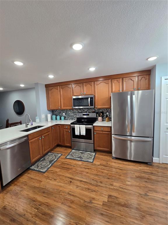 A kitchen features wood cabinets, stainless steel appliances, white countertops, and wood-look flooring — 7600 SUN ISLAND DRIVE S UNIT 306, SOUTH PASADENA, FL