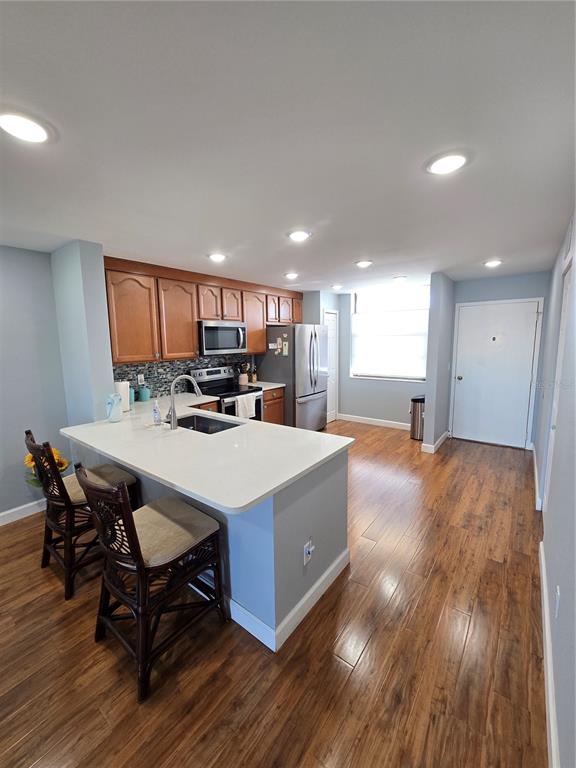 A kitchen features wood cabinets, stainless steel appliances, a white island, and wood-look flooring — 7600 SUN ISLAND DRIVE S UNIT 306, SOUTH PASADENA, FL