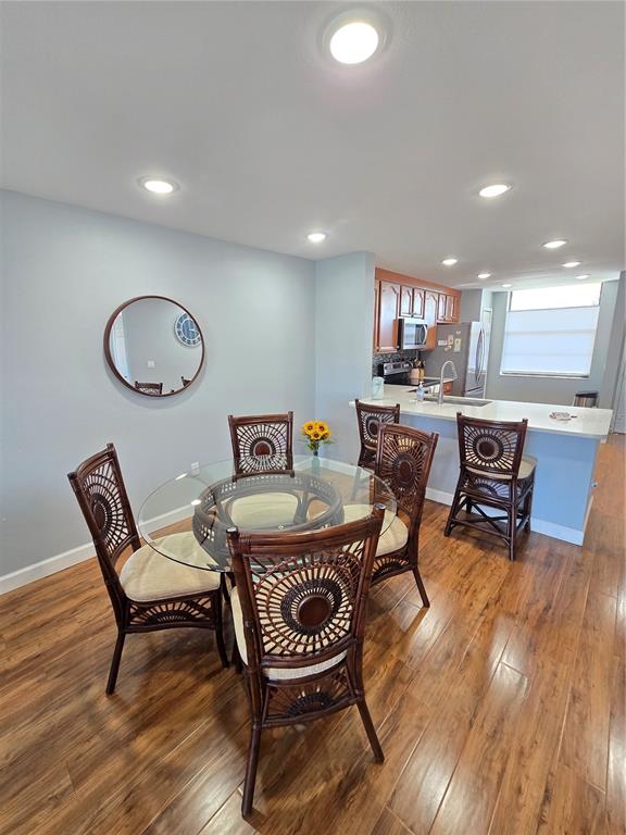 A dining area with a glass-topped table and wicker chairs sits adjacent to a kitchen — 7600 SUN ISLAND DRIVE S UNIT 306, SOUTH PASADENA, FL