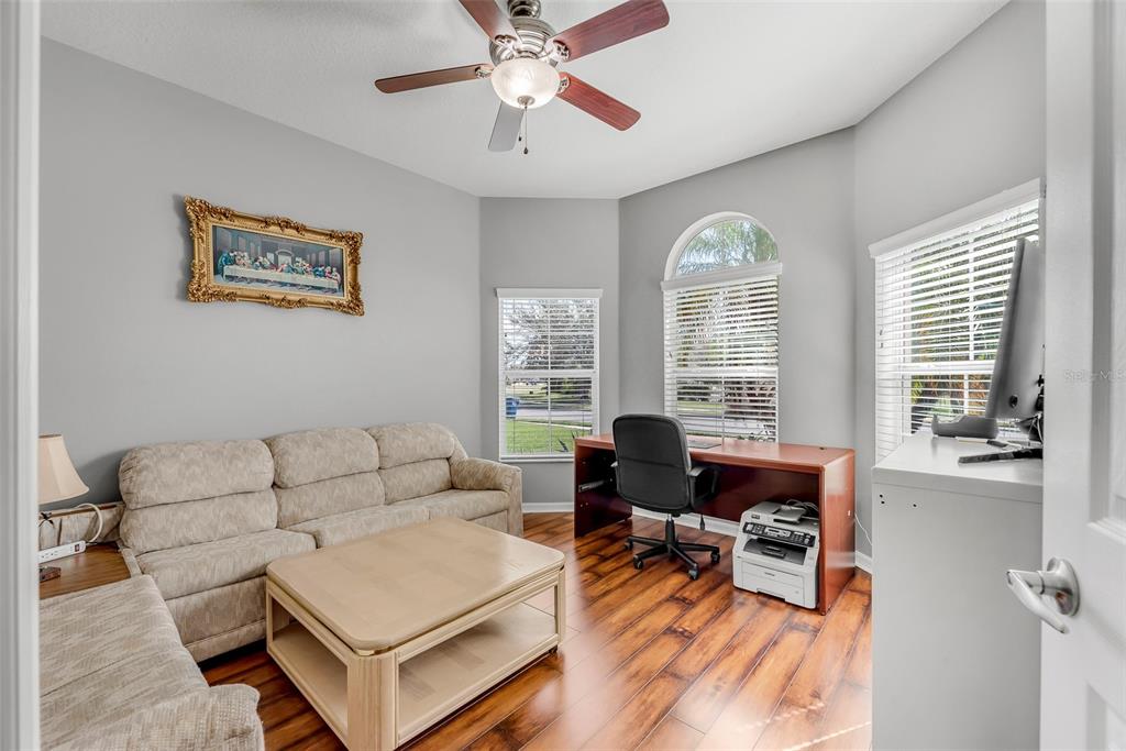 A home office features a beige sofa, a wooden desk, and wood-look flooring — 11236 77TH STREET E, PARRISH, FL