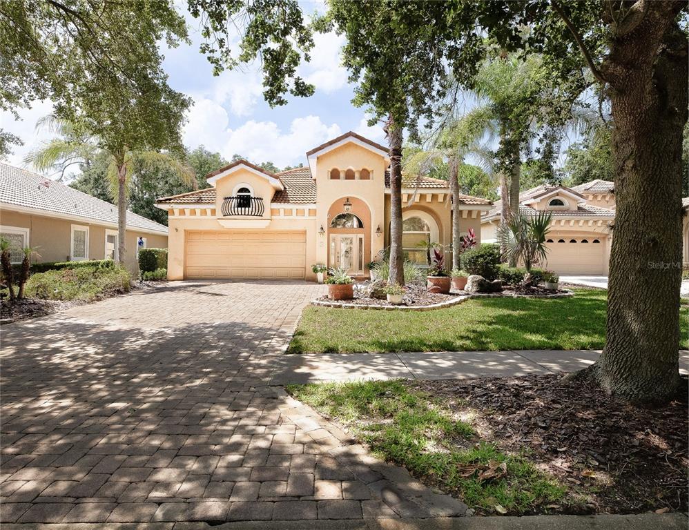 A tan stucco house with a tiled roof, arched entryway, and a paved driveway — 3 VILLAGE VIEW DRIVE, PALM COAST, FL