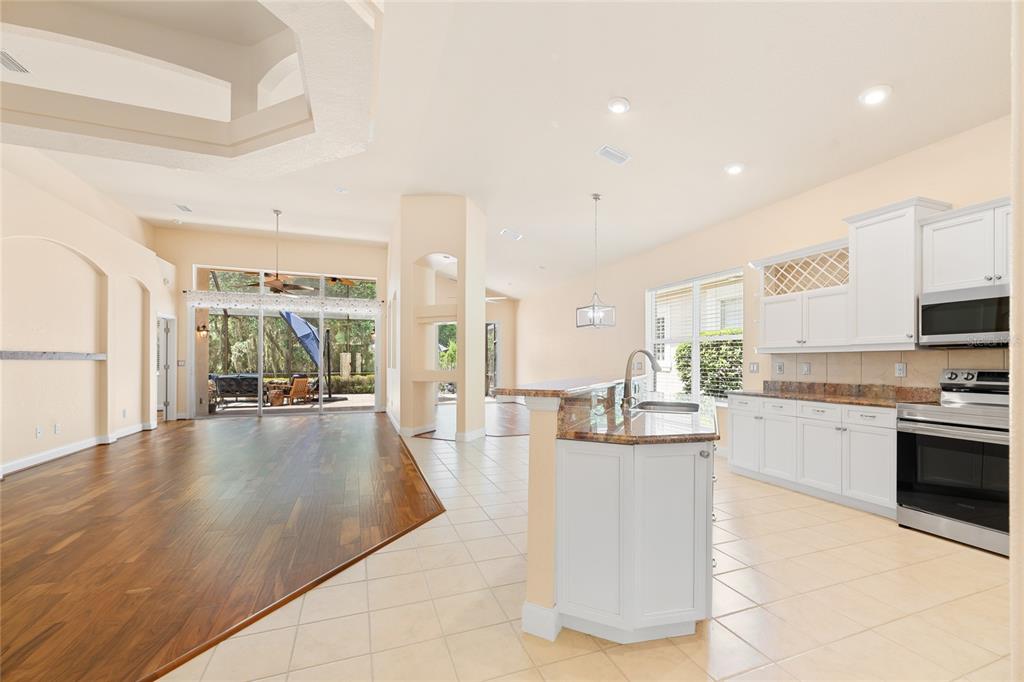 A kitchen with white cabinets and granite countertops opens to a living area with flooring — 3 VILLAGE VIEW DRIVE, PALM COAST, FL