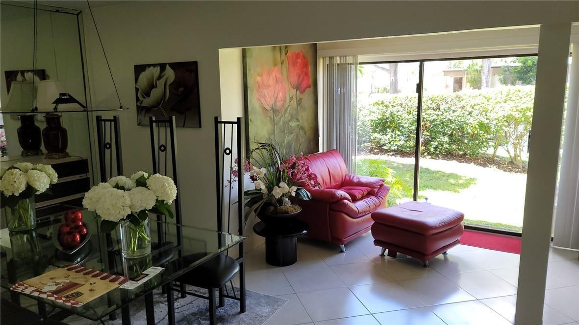 A dining area with a glass table leads to a living space with red furniture — 6574 Burning Wood Drive # 101, Boca Raton FL 33433, BOCA RATON, FL