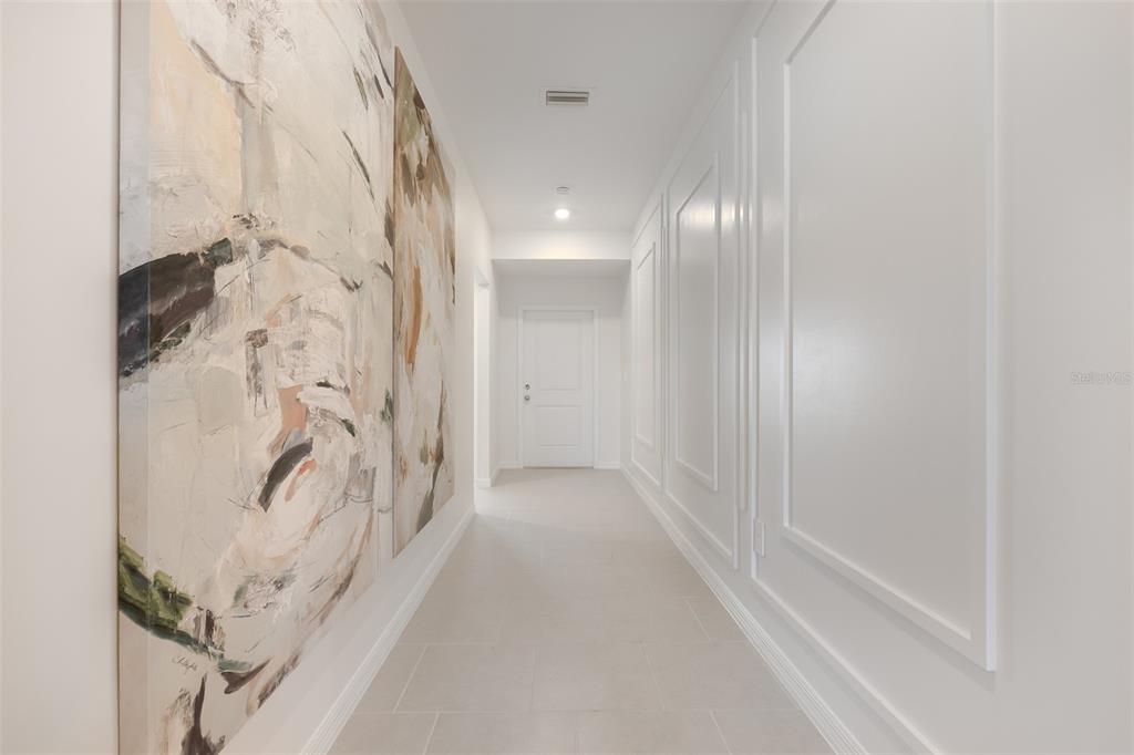 A hallway features large abstract wall art on one side and decorative molding on the other — 11927 BROOKSIDE AVENUE, PORT CHARLOTTE, FL