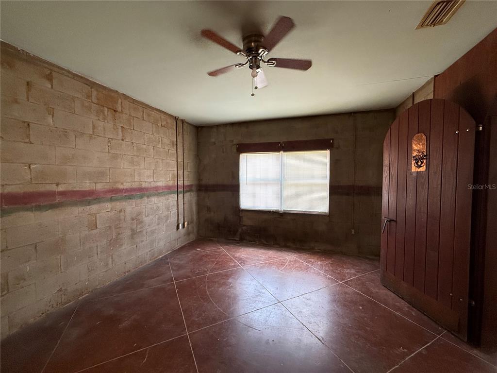 An interior room features exposed concrete block walls, a stained concrete floor, and a ceiling fan — 2308 FERN PALM DRIVE, EDGEWATER, FL