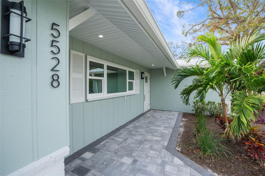 A light green house exterior features a paved walkway, a white front door, and landscaping — 5528 BRIARCLIFF DRIVE, SARASOTA, FL