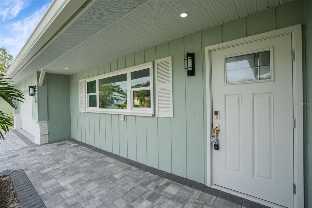 A light green house exterior features a white front door, a window, and paved walkway — 5528 BRIARCLIFF DRIVE, SARASOTA, FL