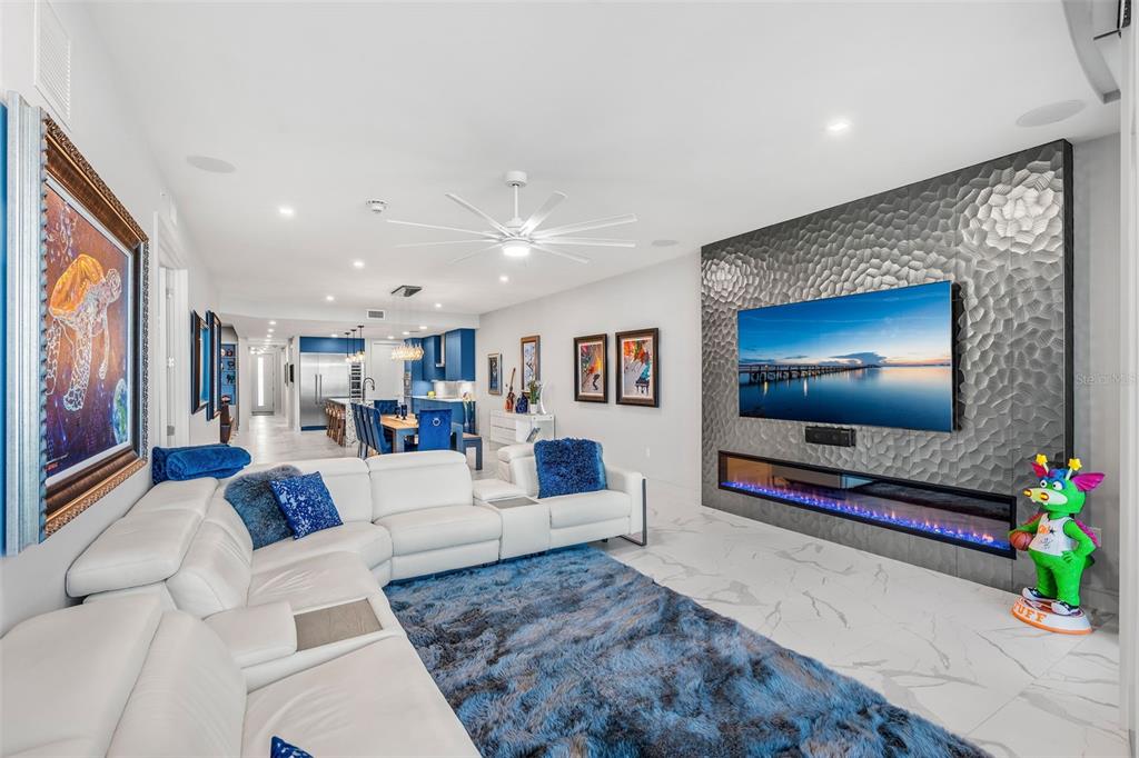 A modern living room features a white sectional, blue rug, and a textured fireplace wall — 65 N ATLANTIC AVENUE UNIT 205, COCOA BEACH, FL