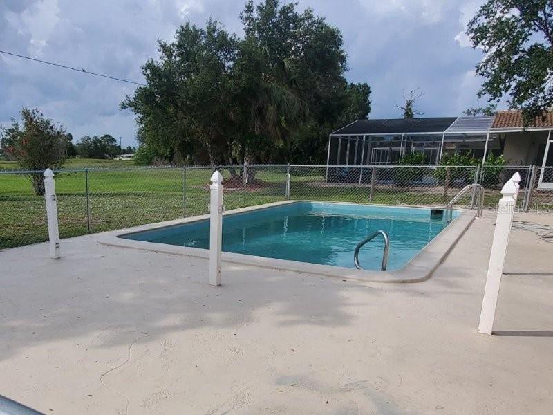 An outdoor swimming pool with a concrete deck is enclosed by a chain-link fence — 2451 AQUILOS COURT, PORT CHARLOTTE, FL