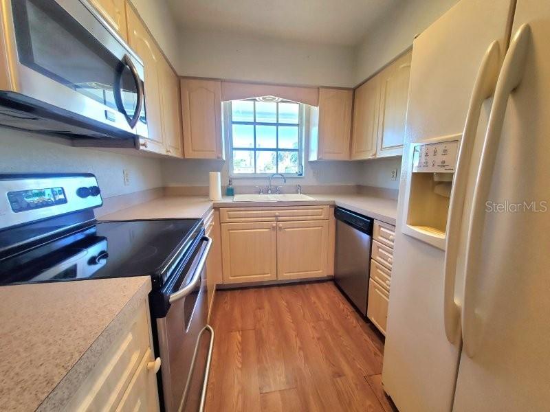 A kitchen features light wood cabinets, stainless steel appliances, and a window above the sink — 2451 AQUILOS COURT, PORT CHARLOTTE, FL