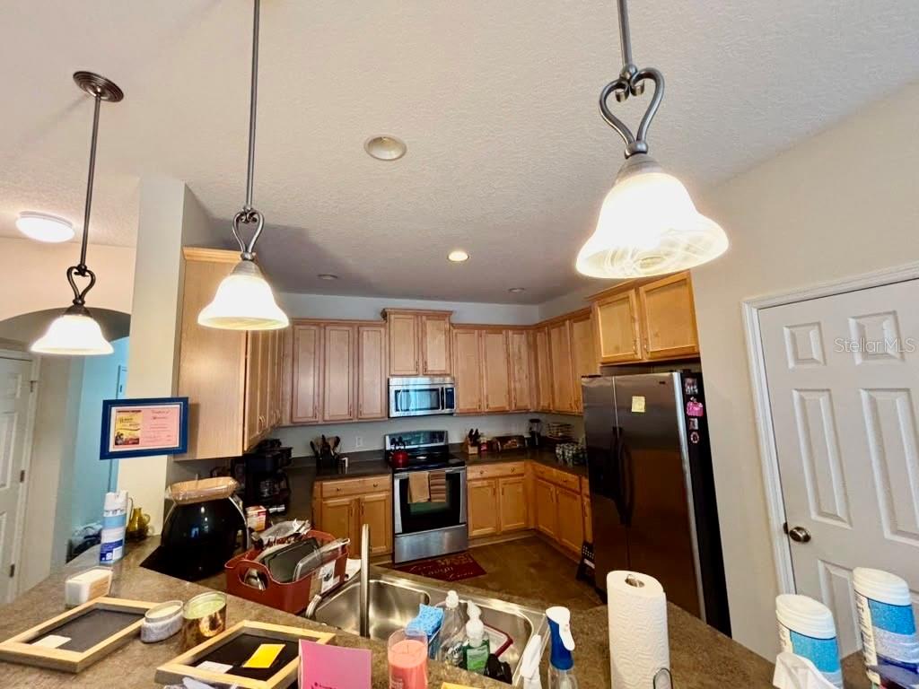 A kitchen features light wood cabinets, stainless steel appliances, and two pendant lights over counters — 3605 SPECKLED WAY, SANFORD, FL