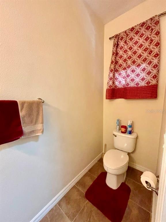 A small bathroom features a toilet, a red rug, and a patterned window curtain — 3605 SPECKLED WAY, SANFORD, FL
