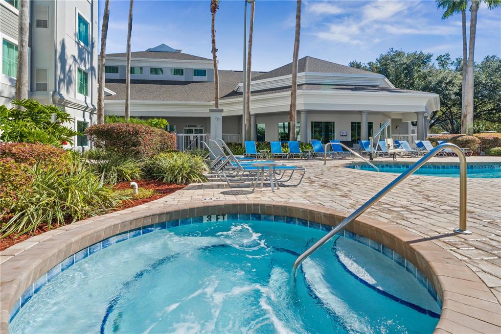A hot tub sits in the foreground of a pool deck with lounge chairs and buildings — 8303 PALM PARKWAY, ORLANDO, FL
