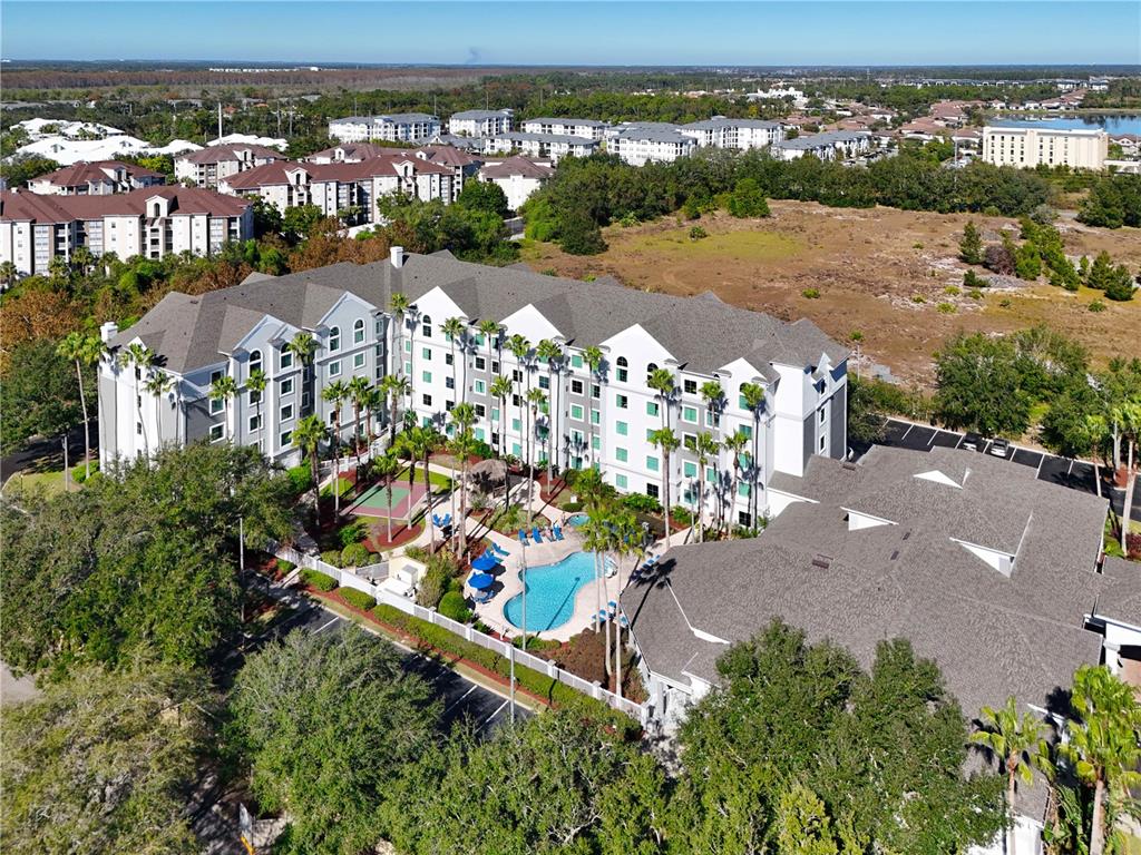 An aerial view shows a multi-story hotel building with an outdoor pool and tennis court — 8303 PALM PARKWAY, ORLANDO, FL