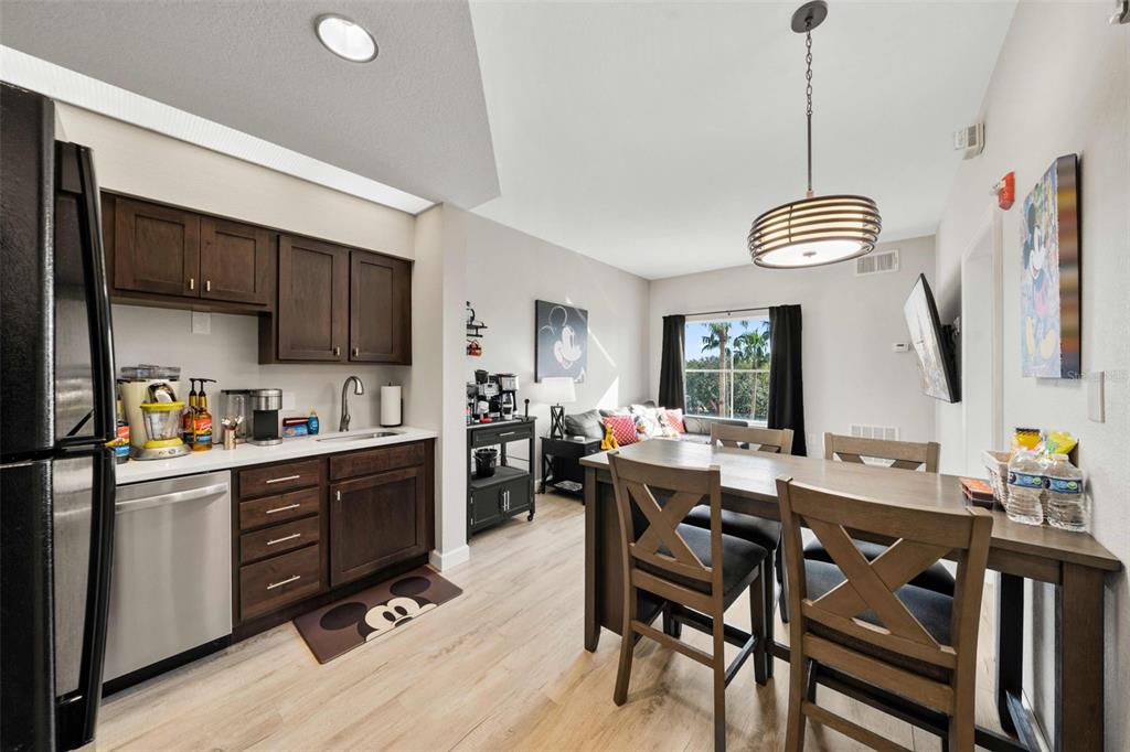 A kitchen and dining area with dark wood cabinets, stainless appliances, and light wood flooring — 8303 PALM PARKWAY, ORLANDO, FL