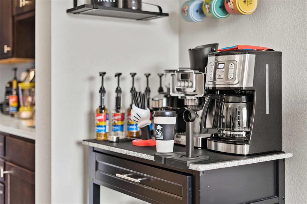 A coffee station features a black coffee maker, syrup bottles, and mugs on a counter — 8303 PALM PARKWAY, ORLANDO, FL