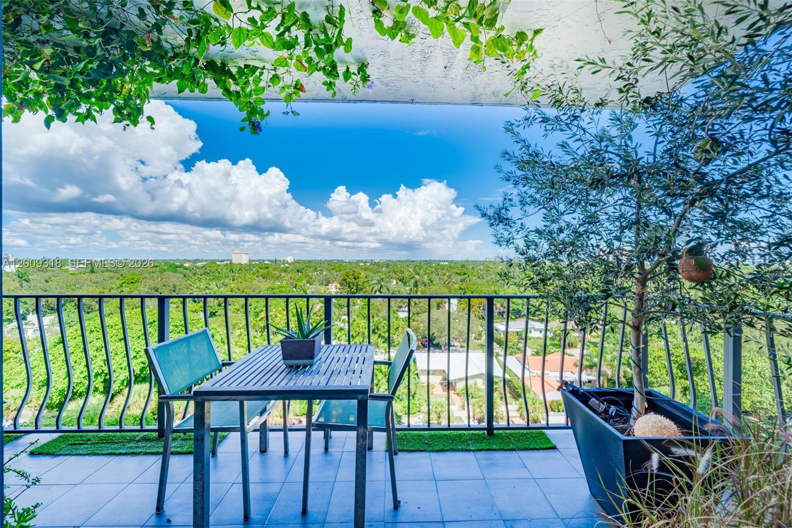 A balcony features a metal table and chairs, a potted tree, and a scenic view — 780 NE 69th St # 808, Miami FL 33138, MIAMI, FL