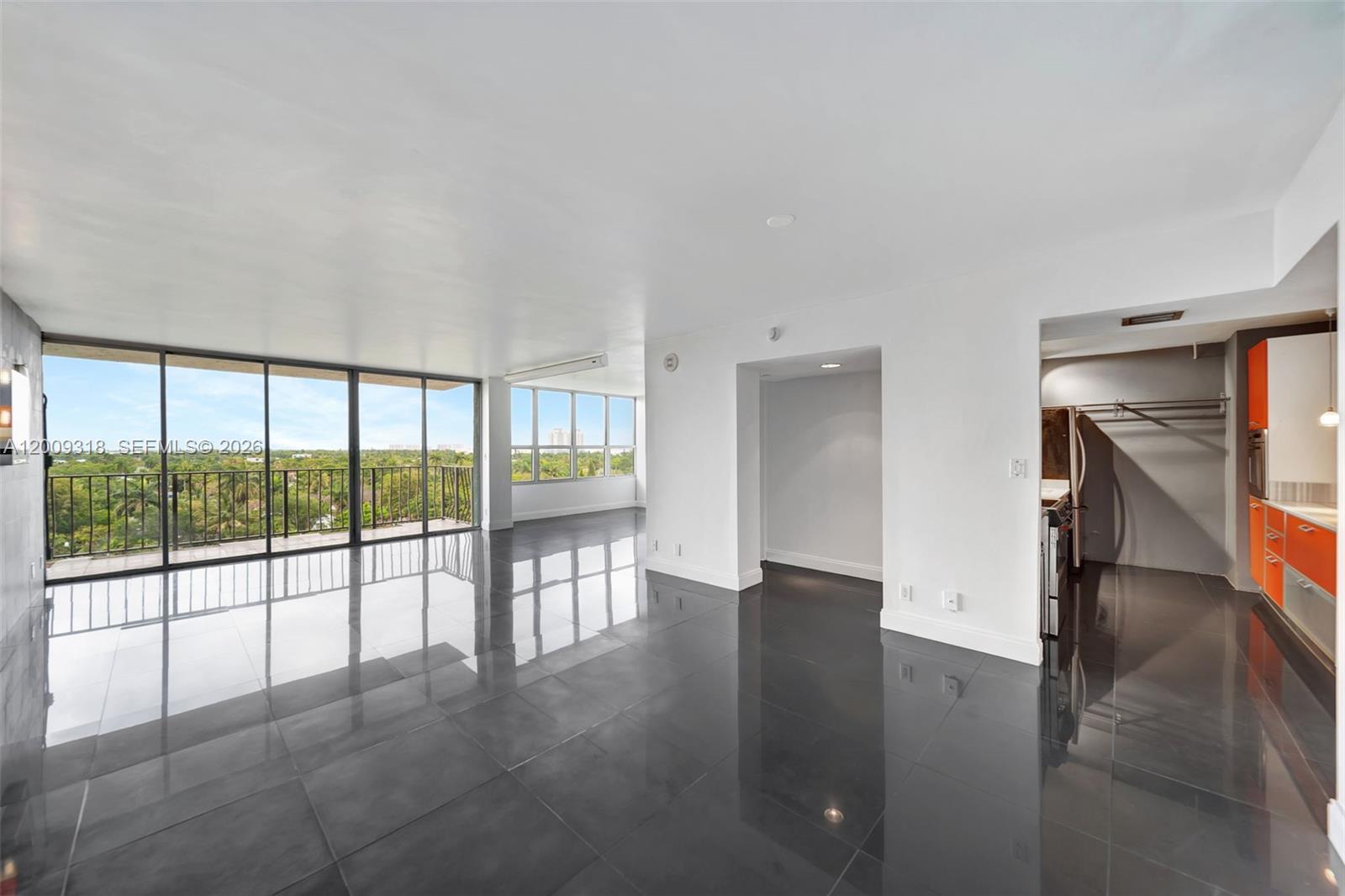 An open-plan living area features dark tile flooring, white walls, and a kitchen with orange cabinets — 780 NE 69th St # 808, Miami FL 33138, MIAMI, FL