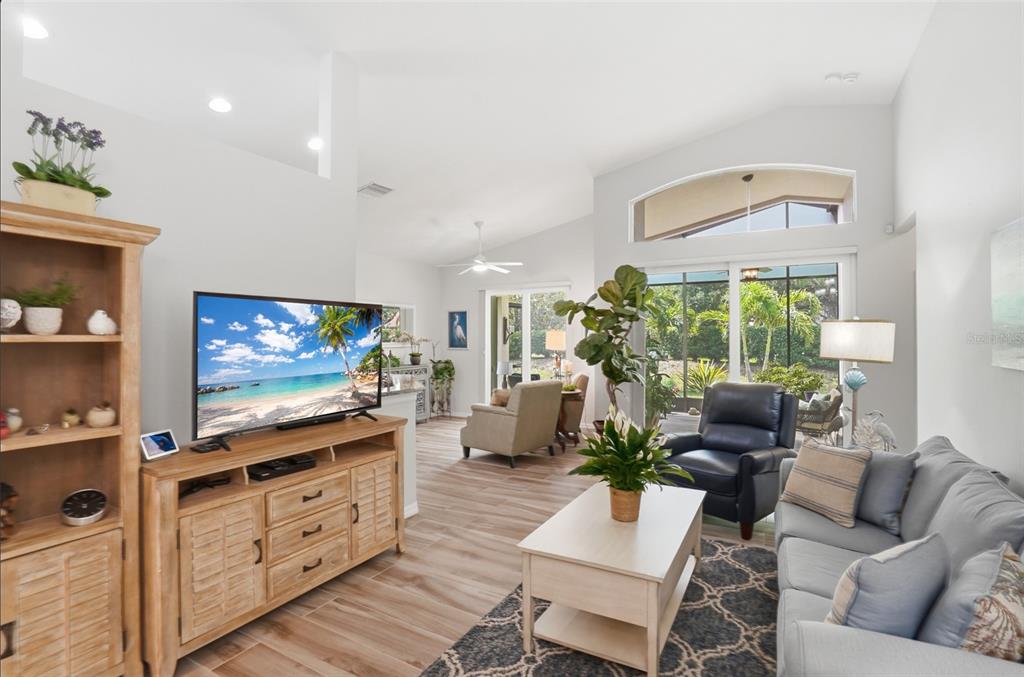 A living room features a television console, a sofa, a recliner, and large sliding glass doors — 4222 65TH PLACE E, SARASOTA, FL