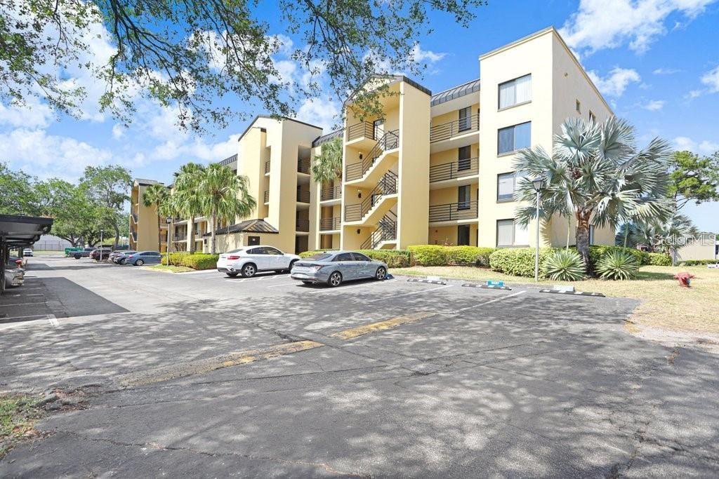 A multi-story yellow apartment building with exterior staircases and a parking lot in front — 2424 W TAMPA BAY BOULEVARD UNIT M205, TAMPA, FL