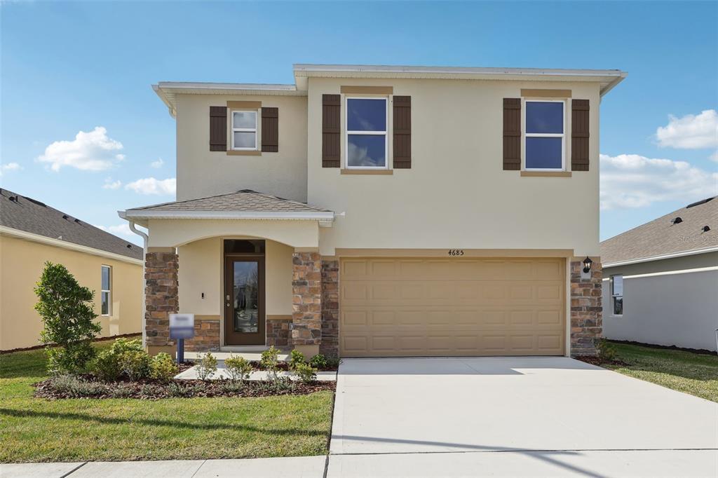 A two-story suburban house with a tan stucco exterior, stone accents, and a two-car garage — 1189 CUMBERLAND TRAIL DRIVE, LAKE HAMILTON, FL